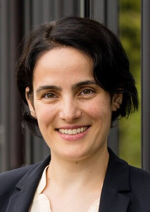 Adrianapaffly Buss mit dunklem Blazer, kurzen dunklen Haaren.